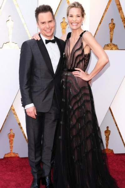 Sam Rockwell, in black Prada and Christian Louboutin shoes, with wife Leslie Bibb on the red carpet Image