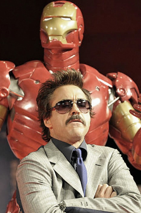 Robert Downey Jr in front of an Iron Man suit