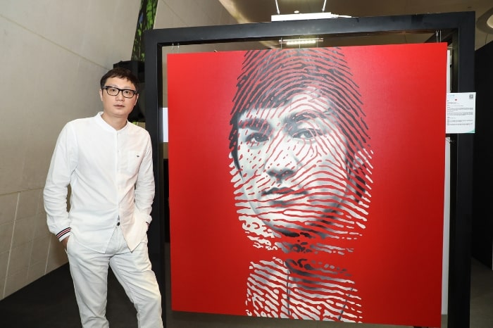 Artist Ren Zhen Yu with his portrait of Bruce Lee at the UNICEF HK art exhibition