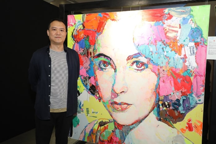 Artist Zou Cao with his portrait of Elizabeth Taylor at the UNICEF HK art exhibition